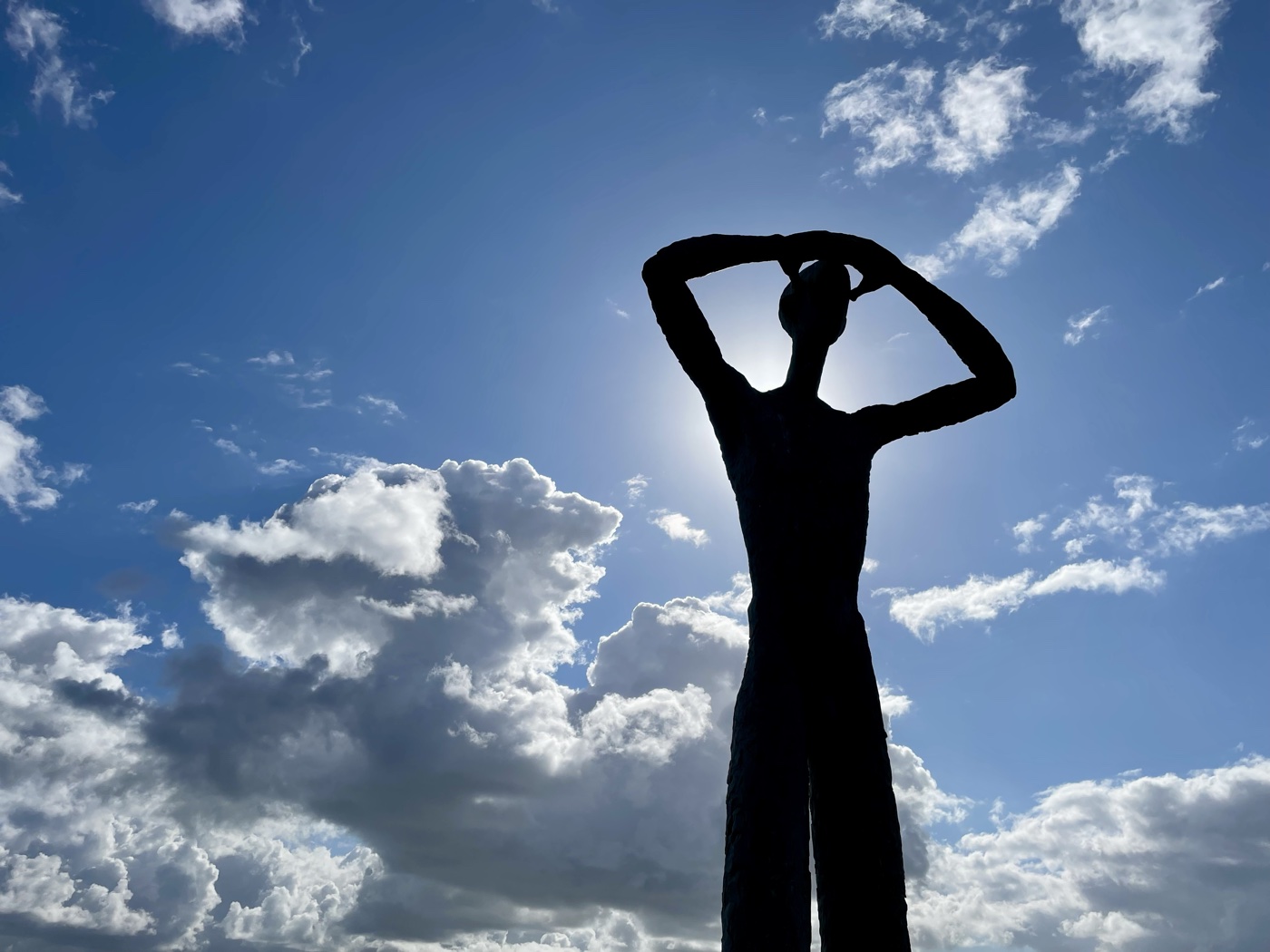 Silhouette einer Kunstfigur vor dramatischem Wolkenhimmel